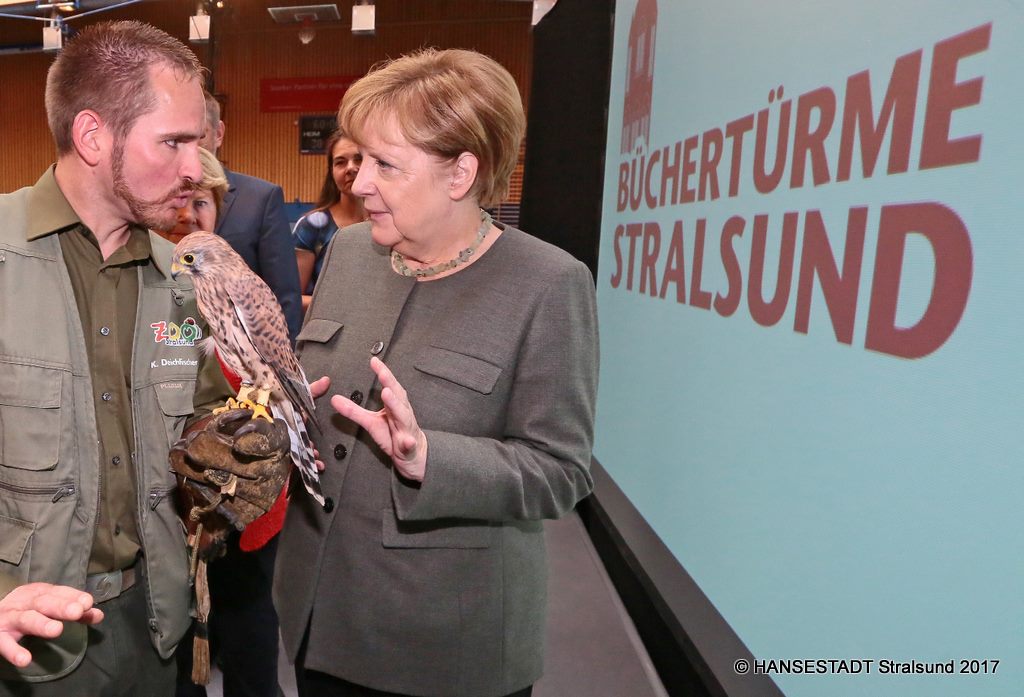 Kay Deichfischer aus dem Stralsunder Zoo hält das Maskottchen der Leseaktion, einen Turmfalken, auf der Hand und erläutert MdB Dr. Angela Merkel, wie dieser Vogel gehalten wird.
